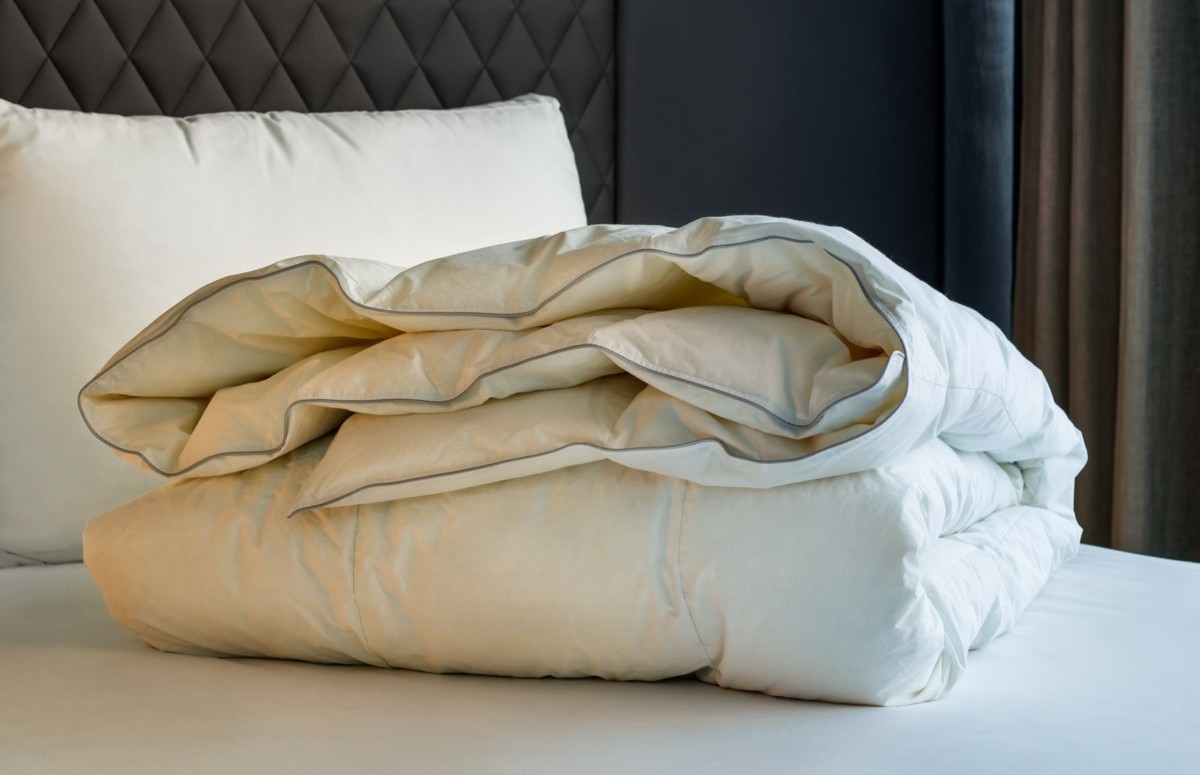 摺疊整齊並放置在床上的白色羽絨被特寫。